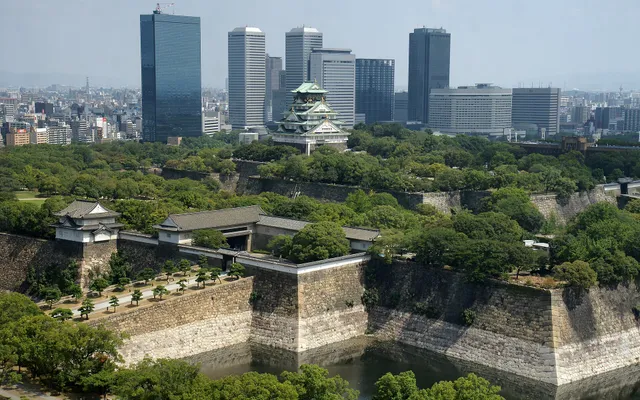 Le château d’Osaka au milieu de ses douves et des arbres, devant les gratte-ciel de la ville