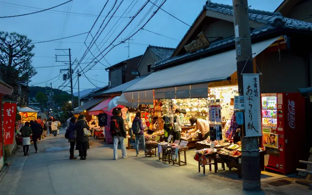 Une boutique de souvenirs ouverte sur une rue commerçante traditionnelle au Japon, à la tombée du jour